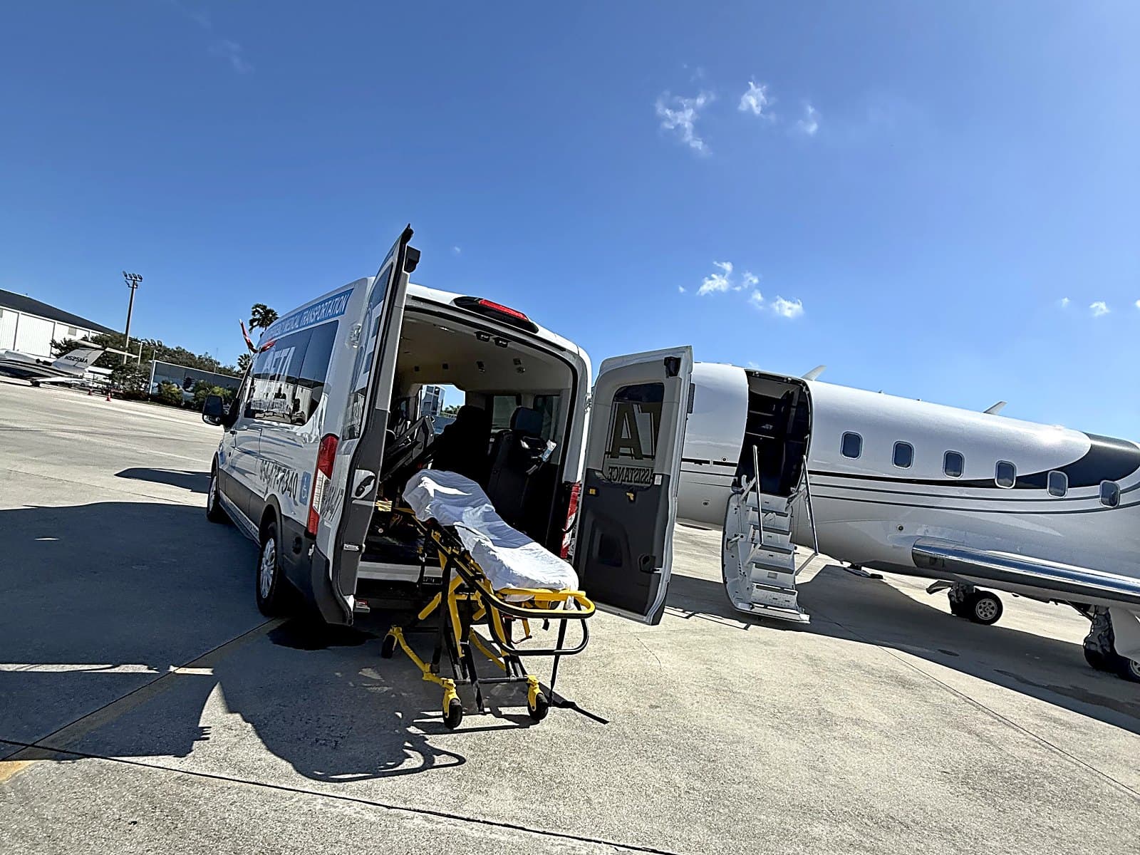 Essential Transport Assistance stretcher ready at the open door of a private jet at Signature Aviation, Palm Beach International Airport